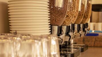 A coffee station with multiple dispensers filled with coffee beans and grounds, surrounded by stacked white plates and clear glasses.