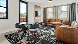 Una sala de estar moderna con una mesa de vidrio, sofá de cuero y un televisor de pantalla plana.