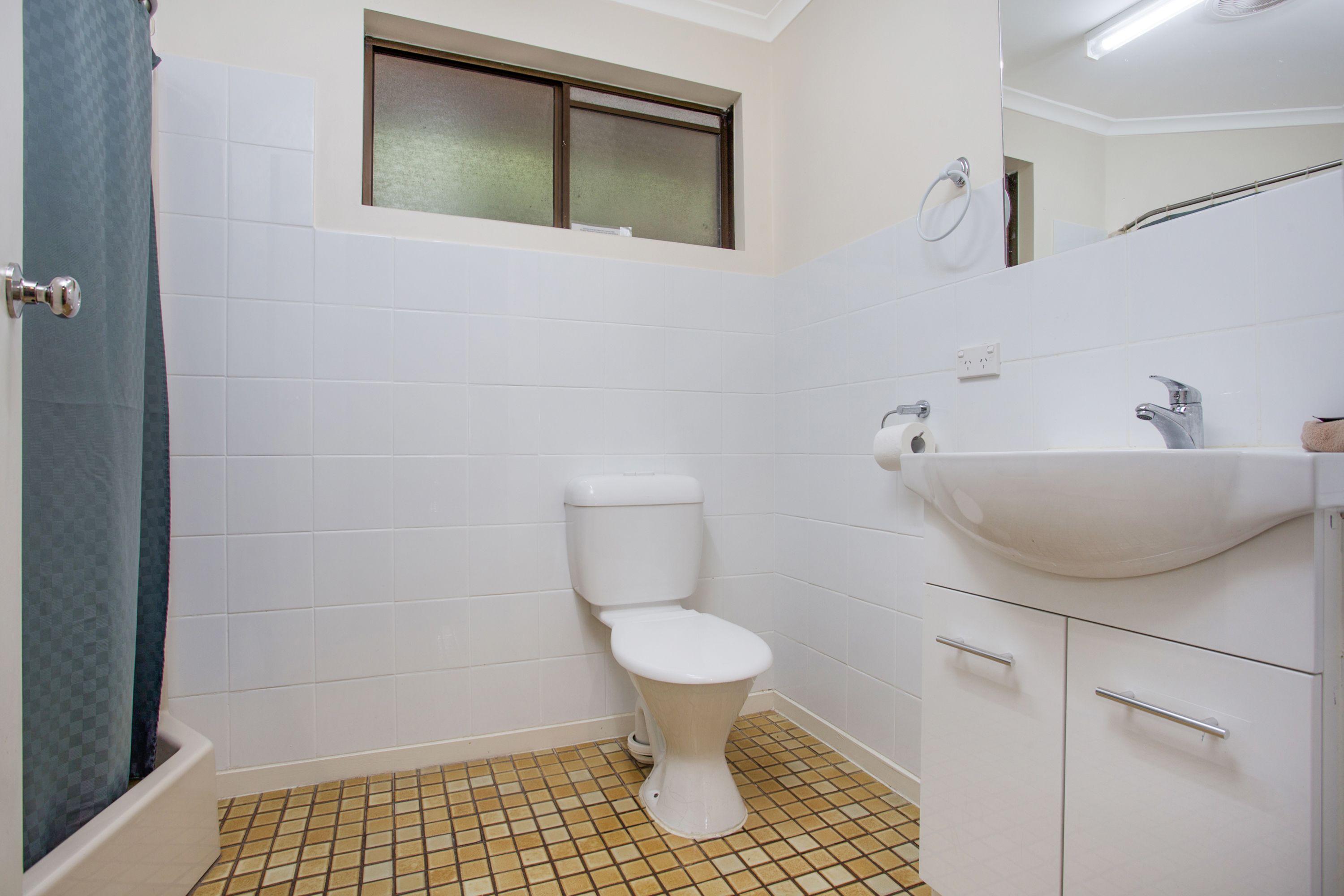 Un bagno con il water, lavandino e pavimento piastrellato.