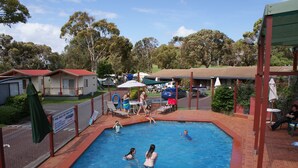 A swimming pool area with a fenced deck, lounge chairs, and a sign indicating pool rules. - Warrnambool Motel and Holiday Park (Warrnambool)