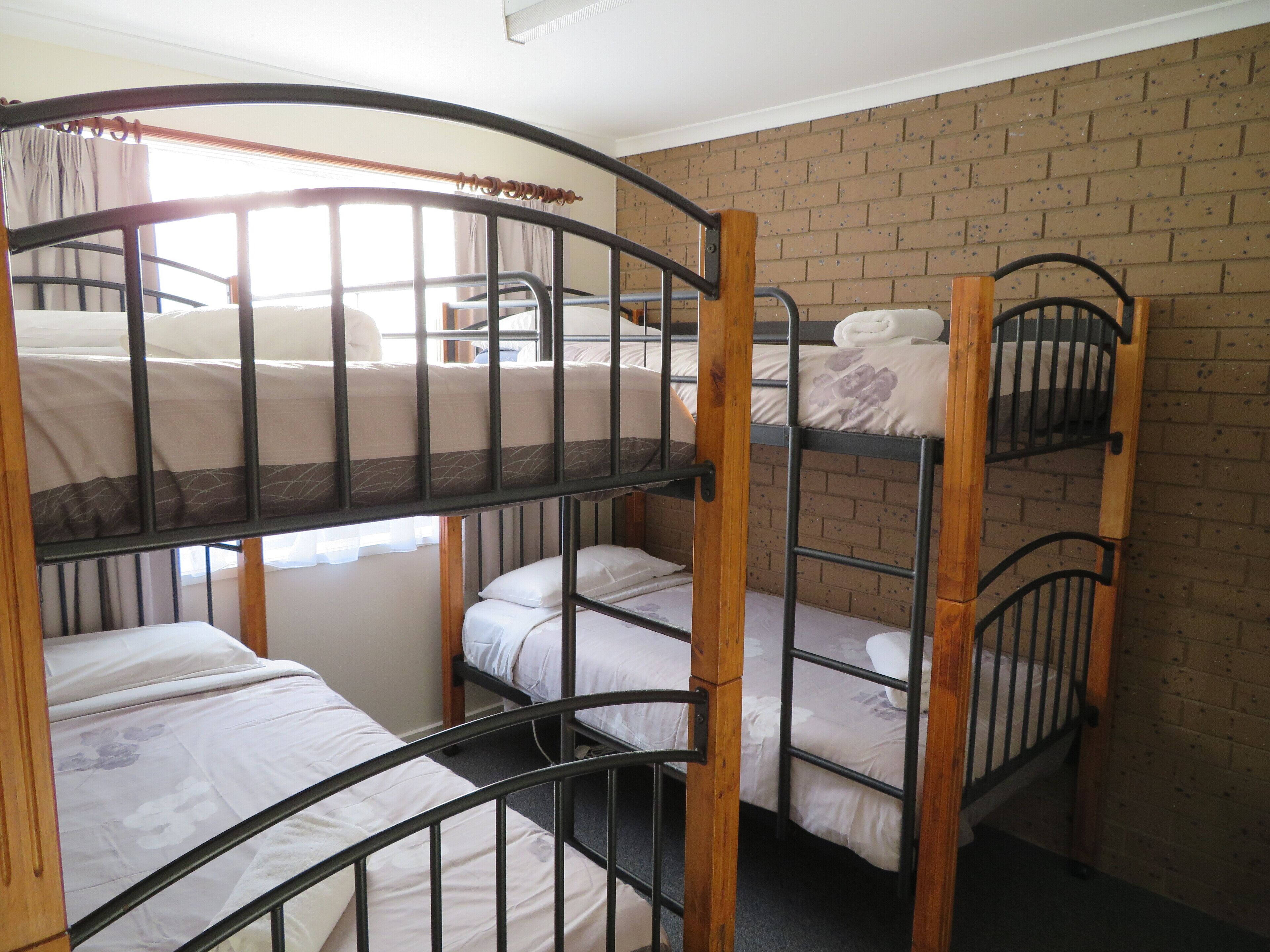 A bunk bed room with a brick wall and a window with curtains.