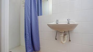 A bathroom with a white sink, a blue shower curtain, and white tiled walls.