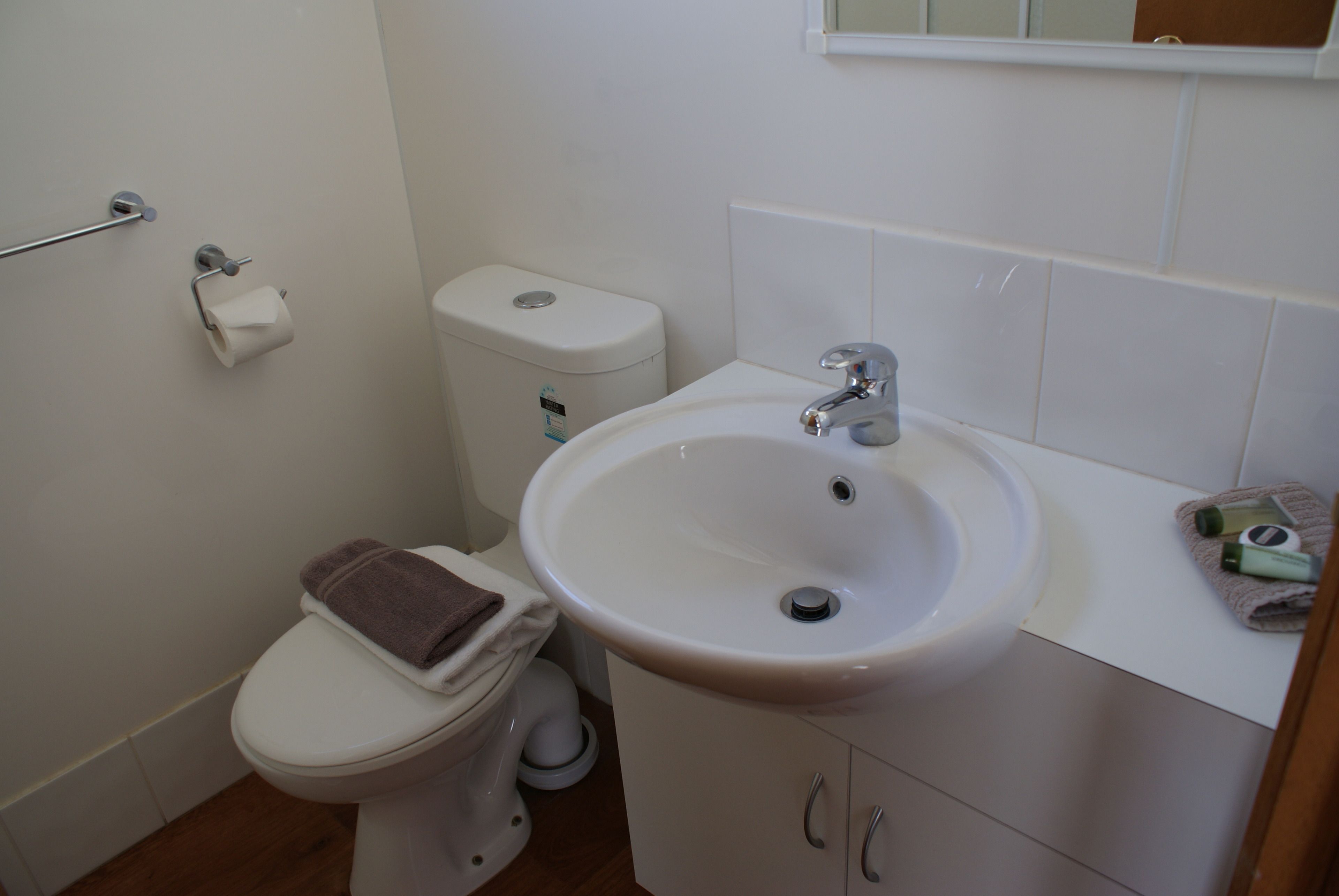 Un baño con inodoro, lavamanos y perchero para toallas.