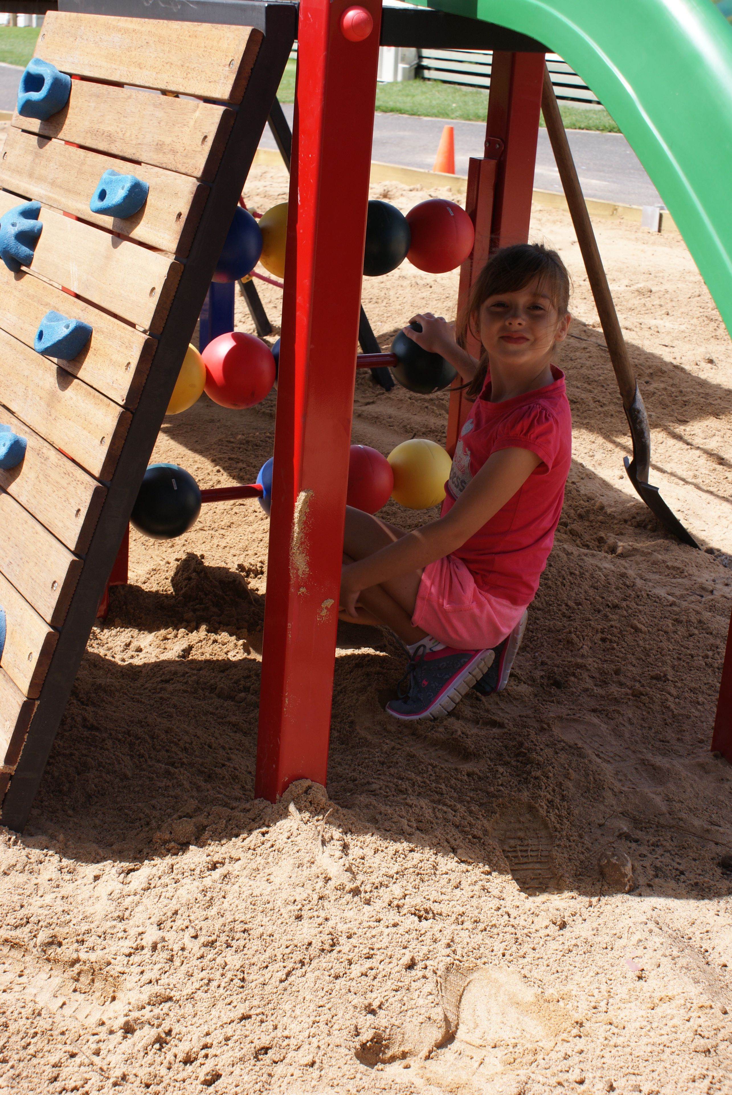 Un enfant joue sur une structure de jeux d’enfants, qui comprend des prises d’escalade et un toboggan.