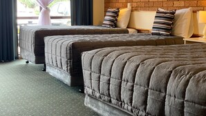 Een hotelkamer met twee bedden, een bakstenen muur en een raam met gordijnen.