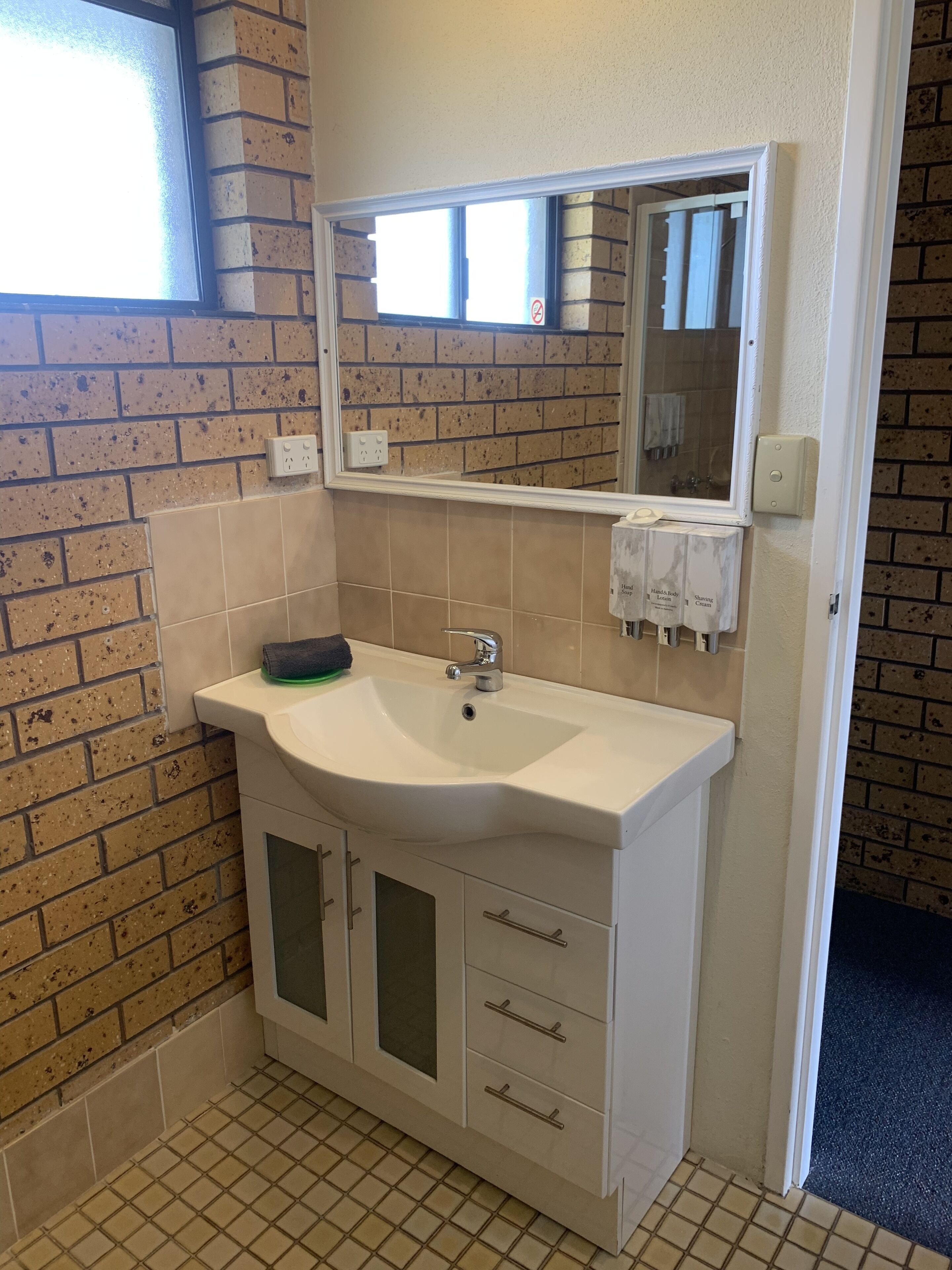 Un bagno con un lavandino bianco, uno specchio e un portasciugamani.