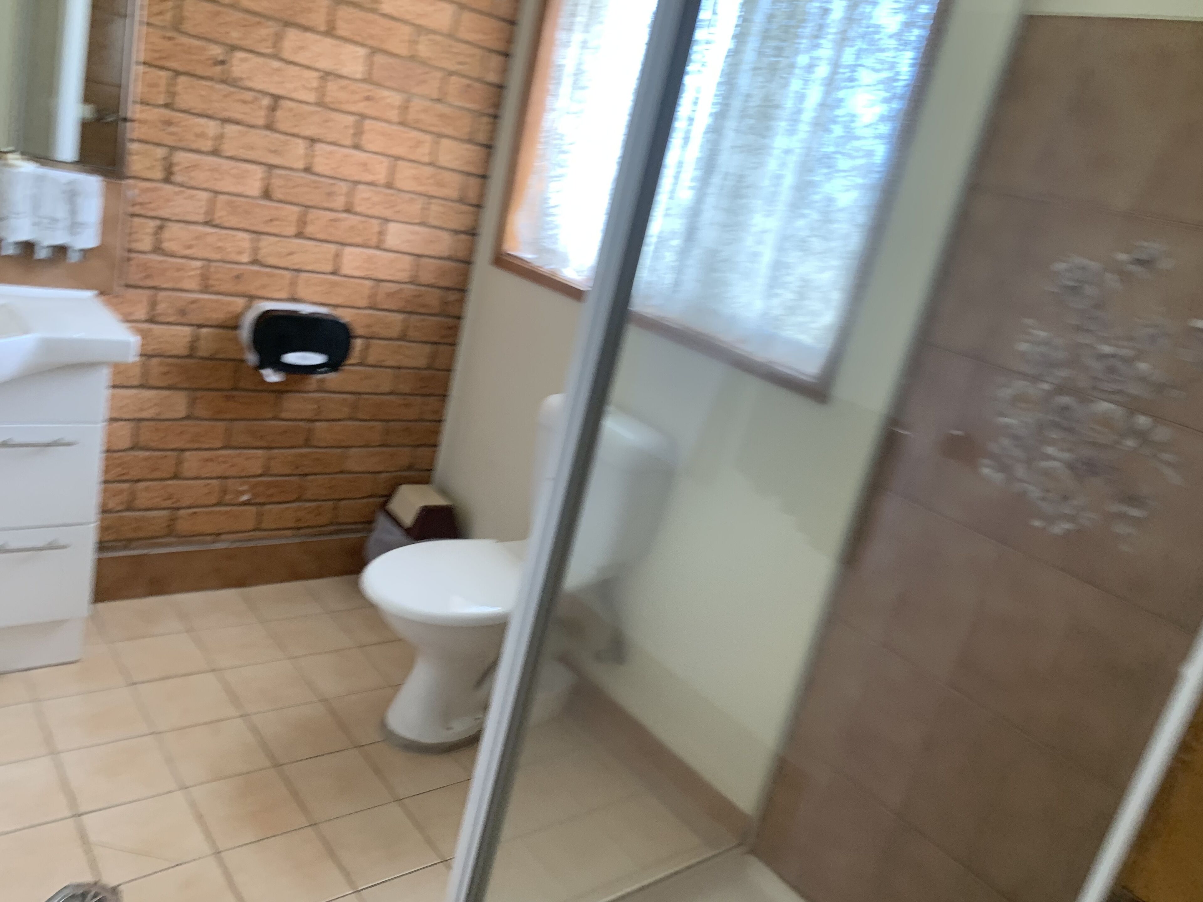 Ein Badezimmer mit Toilette, Handtrockner und Fliesenboden.
