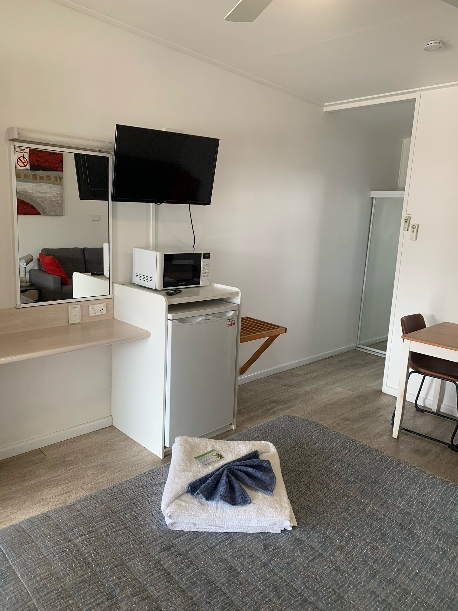 Een compacte hotelkamer met kitchenette, een flatscreen televisie boven de counter, een kleine koelkast en een magnetron.