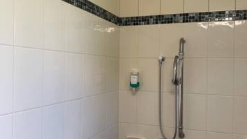 A shower area with a handheld showerhead, a handheld shower attachment, a soap dispenser, and a towel rack.