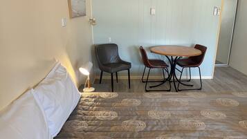 A room with a bed, a table with chairs, a lamp, and a door with a lock.