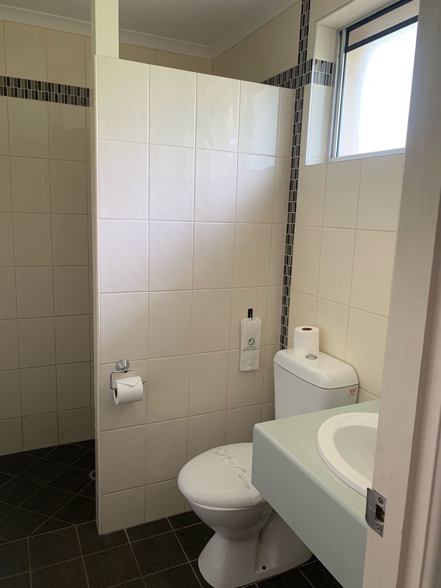 A bathroom with a toilet, a sink, and a paper towel dispenser.