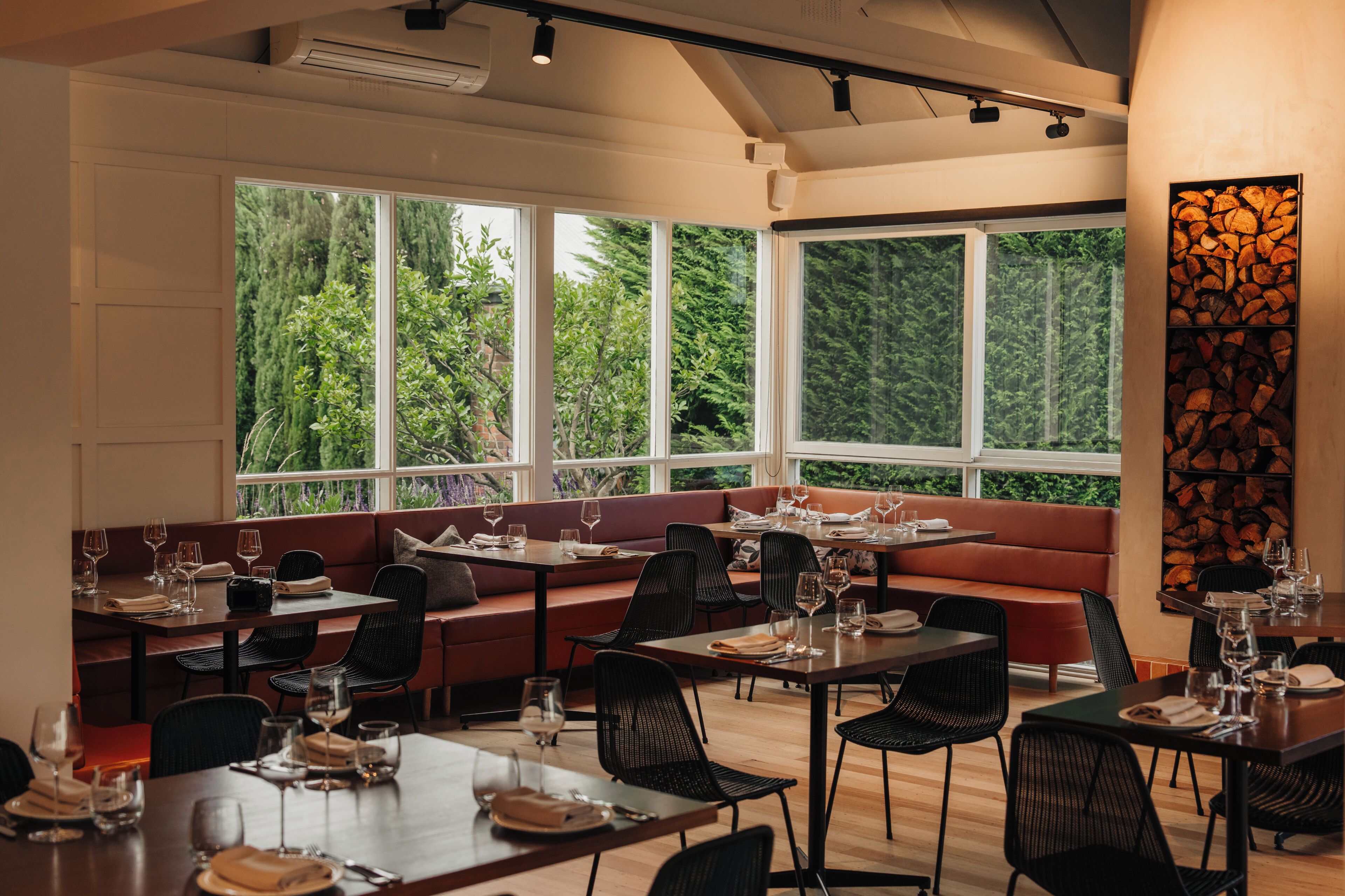 A restaurant with a modern interior, featuring a mix of seating options including tables and a long bench.