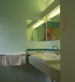 A bathroom with a large mirror, a sink, and a towel rack. - Albion Motel Hotel (Castlemaine)