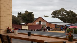 A brick building with a sign for Wesley Hill Market, outdoor seating, and a bicycle parked outside. - Albion Motel Hotel (Castlemaine)