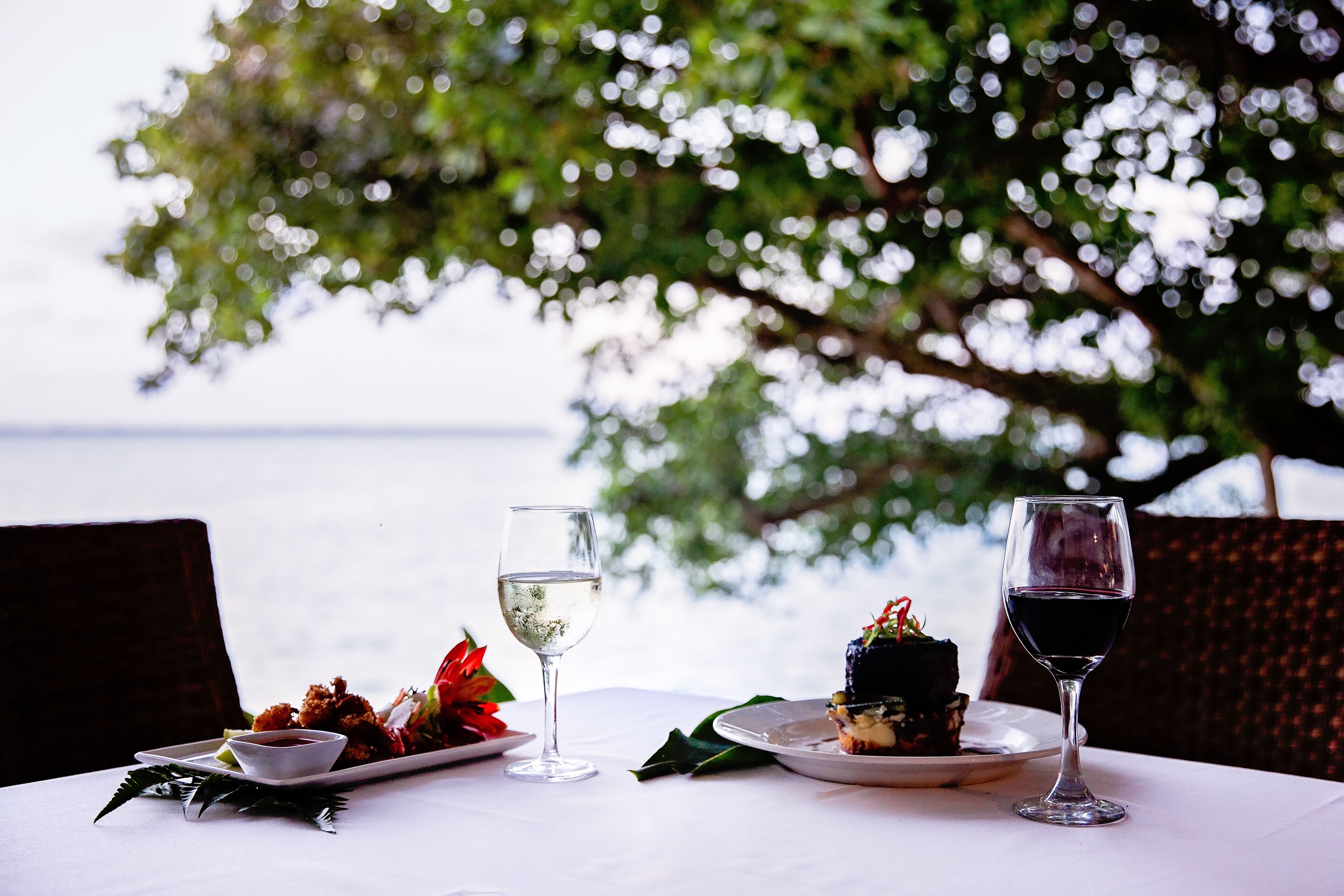 A table set with a plate of food, two glasses of wine, and a decorative centerpiece.