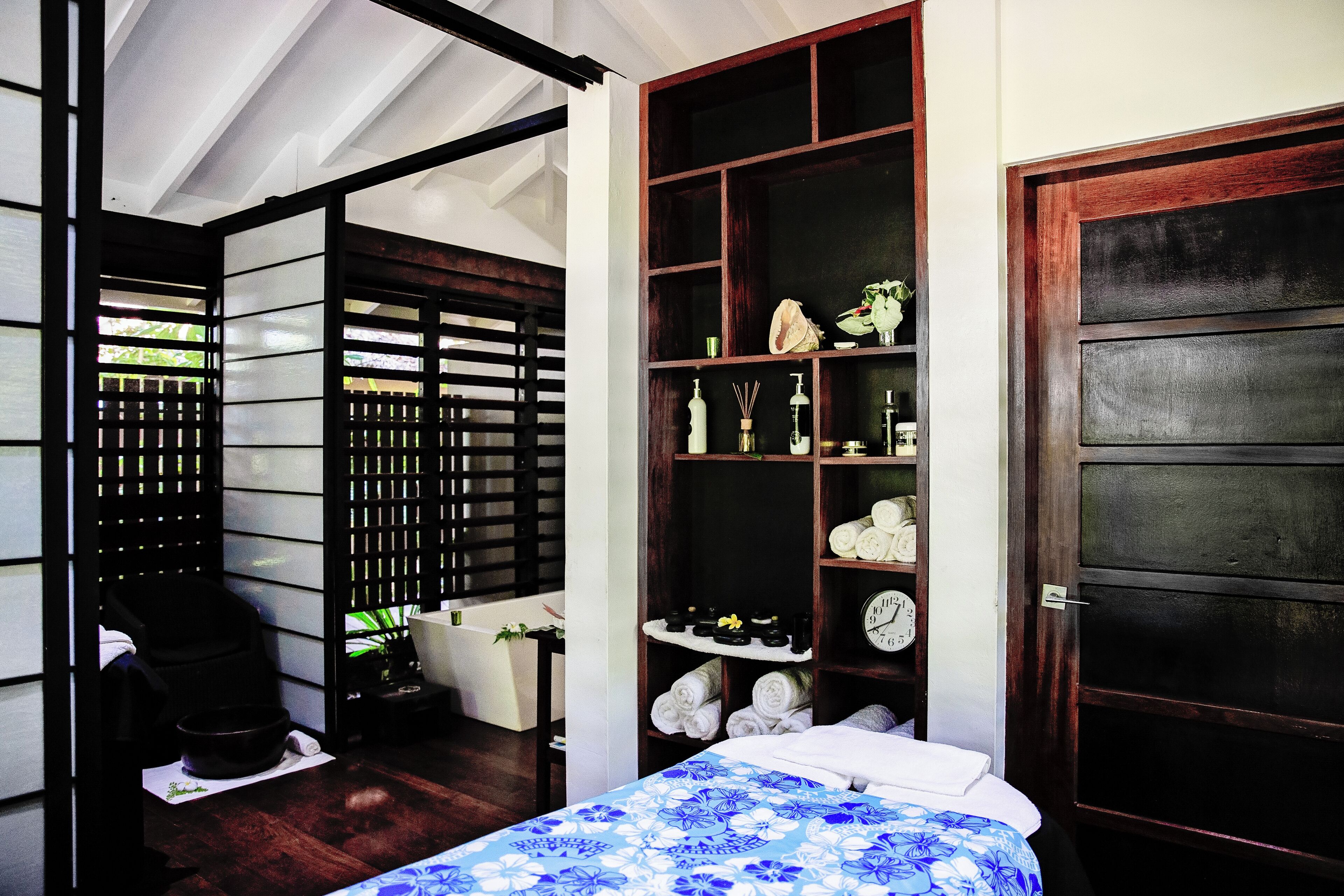 Une chambre à coucher avec un lit, une étagère contenant des articles de toilette et une porte en bois.