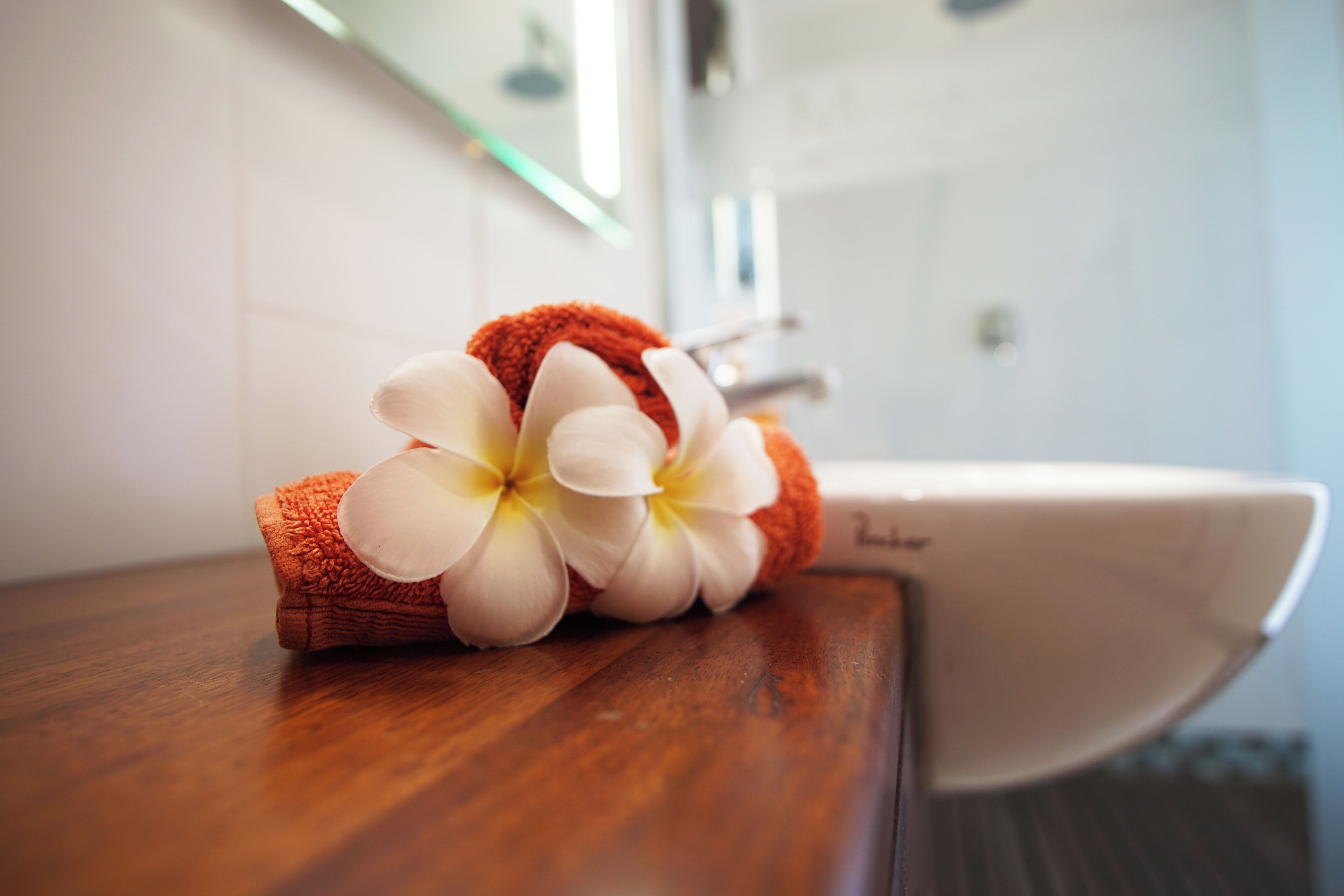 Un baño con encimera de madera, un lavabo blanco y una toalla con un estampado floral.