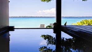 Vista desde un balcón con piscina, con vistas a un mar azul y una costa lejana.