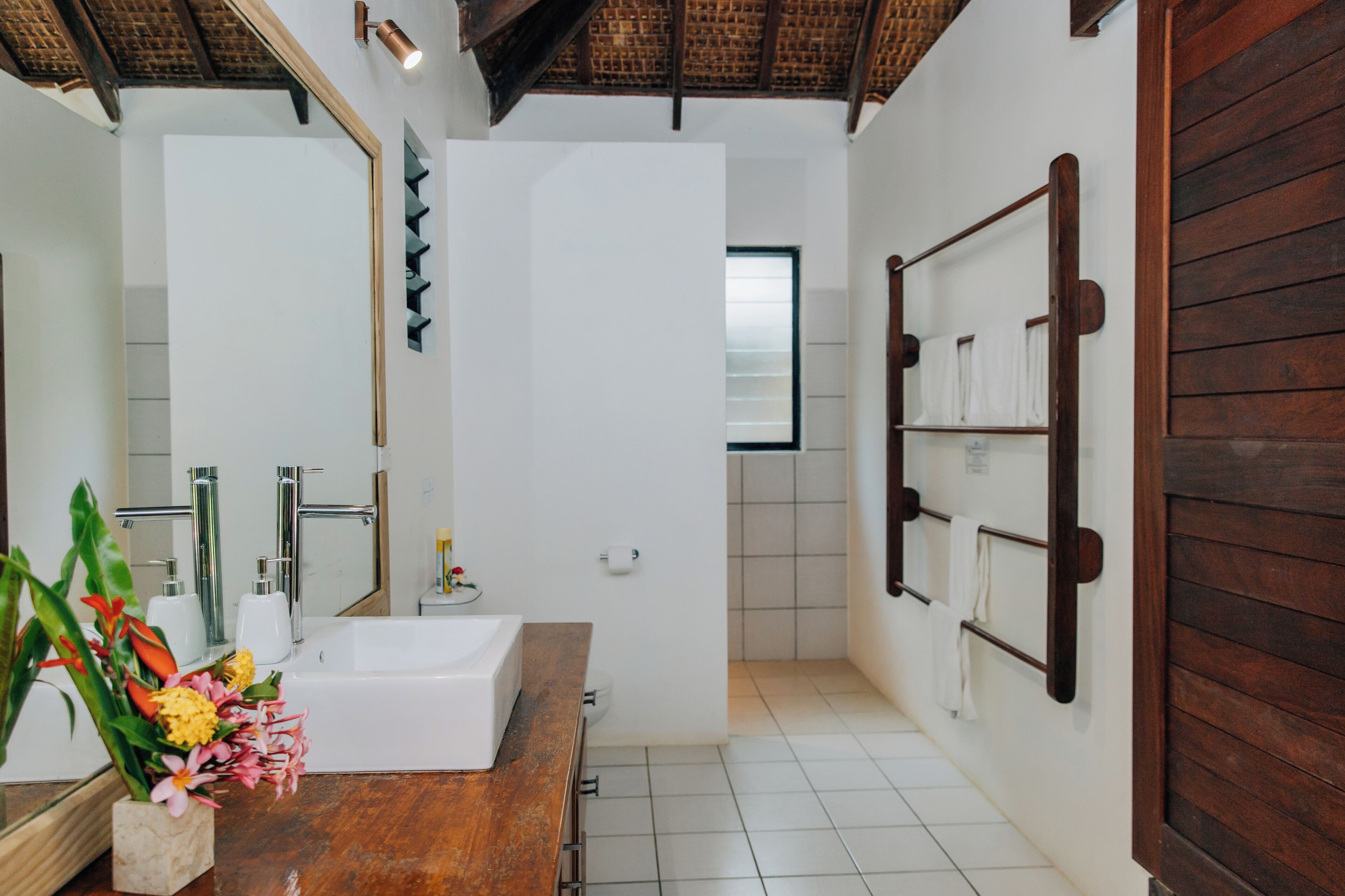 Un baño moderno con tocador de madera, un espejo grande, una bañera blanca y zona de ducha.