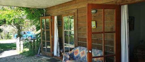 A covered porch with a stone floor, wooden walls, and a patterned sofa.