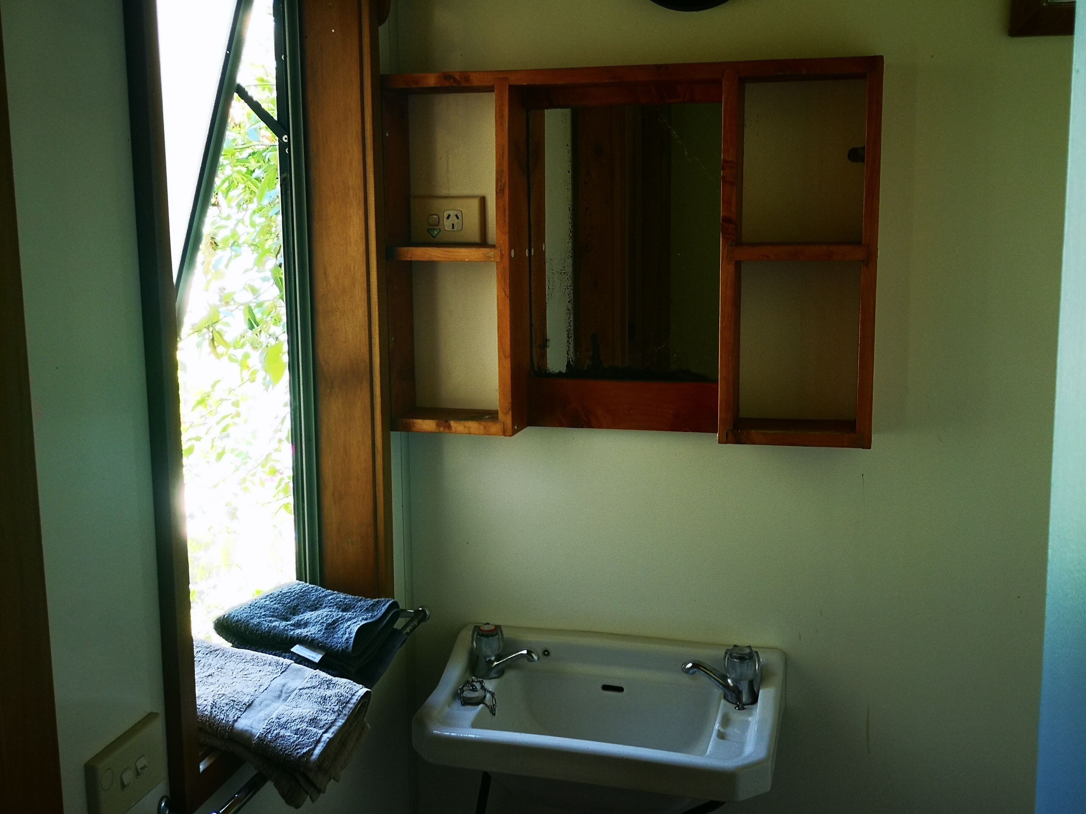 A bathroom with a sink, mirror, and towel rack.