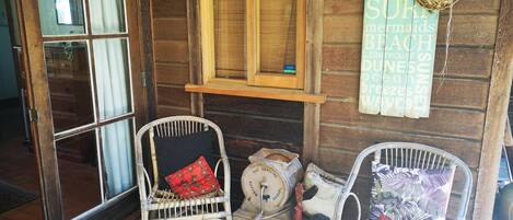 A rustic wooden cabin with two wicker chairs, a small table, and a barrel.