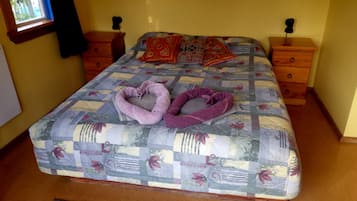 A bed with a quilted bedspread, two heart-shaped towels, and two pillows.