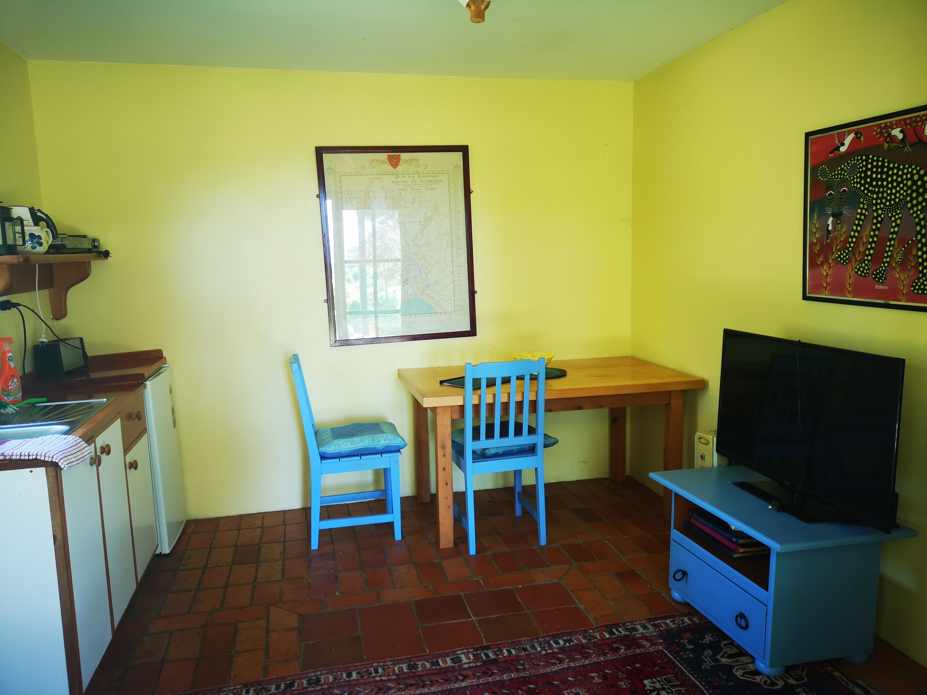 A small room with a desk, a chair, a television, and a map on the wall.