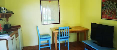 A small room with a desk, a chair, a television, and a map on the wall.