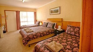 Una habitación de hotel con dos camas, un escritorio y una ventana con cortinas.