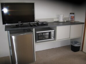 A compact kitchenette with a microwave, a coffee maker, and a small refrigerator.