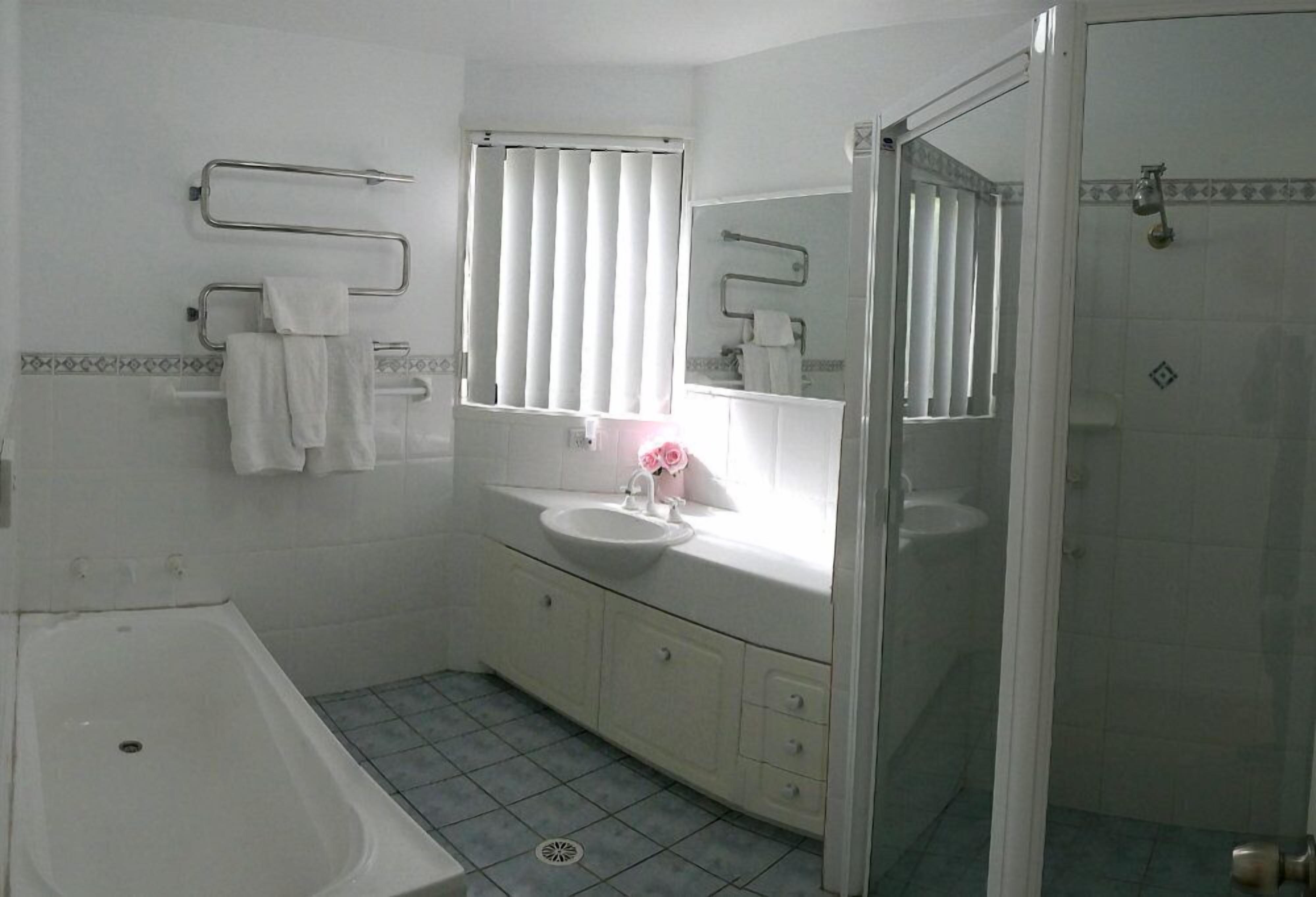 Un baño con bañera, lavamanos, espejo y ducha.