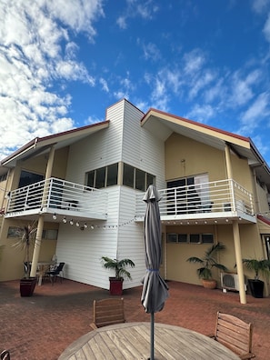 A two-story building with a balcony, outdoor seating, and potted plants. - Pelicans Albany (Middleton Beach)