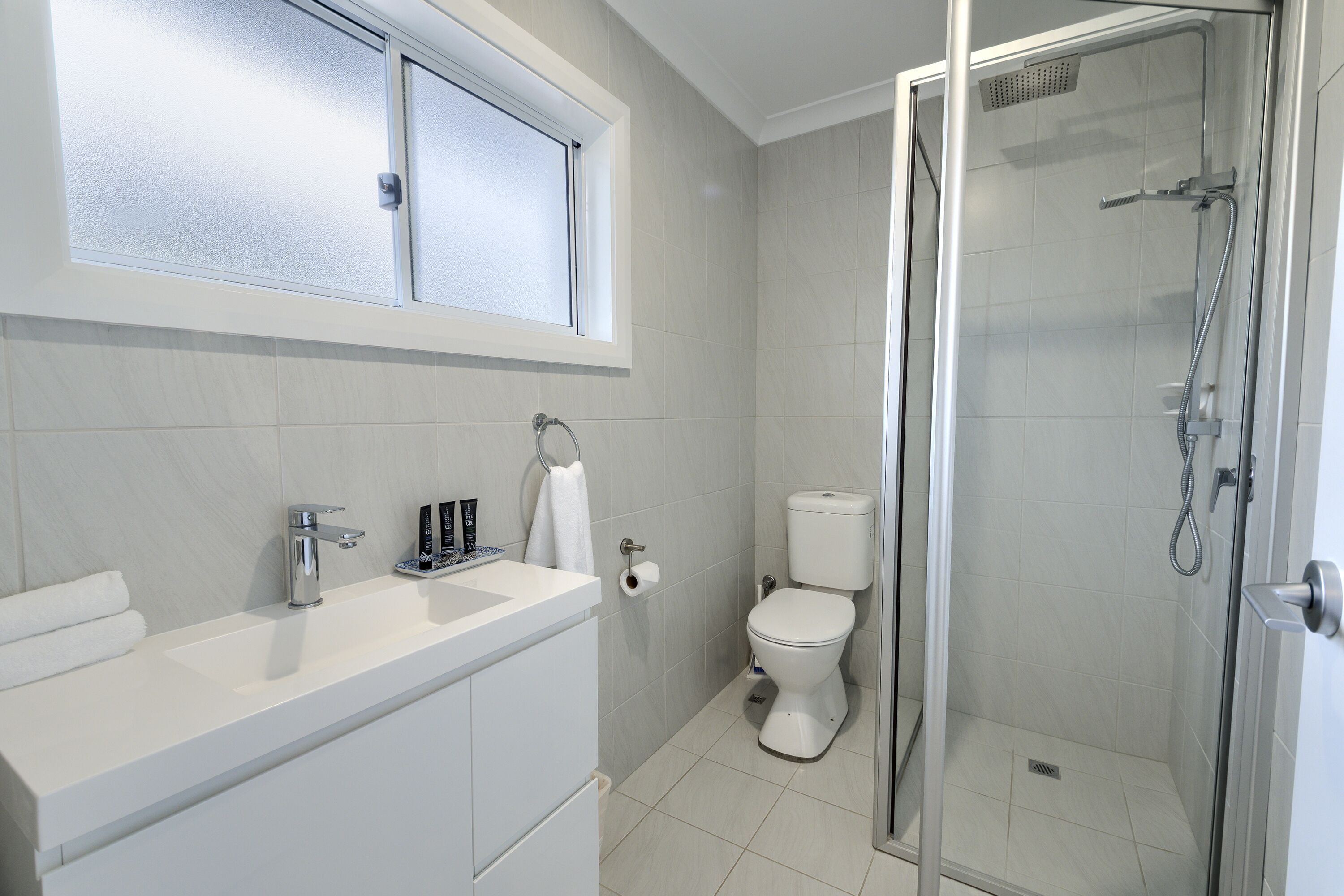 A bathroom with a shower, toilet, and sink.