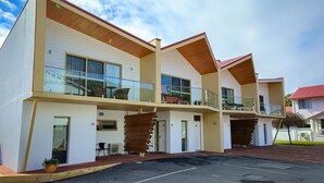 A modern multi-story hotel with balconies, large windows, and a parking area.