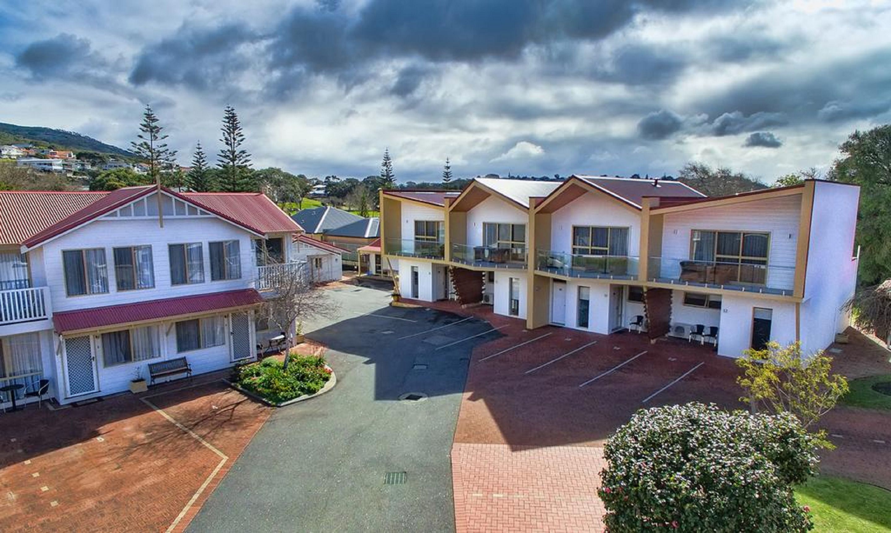 A motel with two-story buildings, a parking lot, and a small garden area.