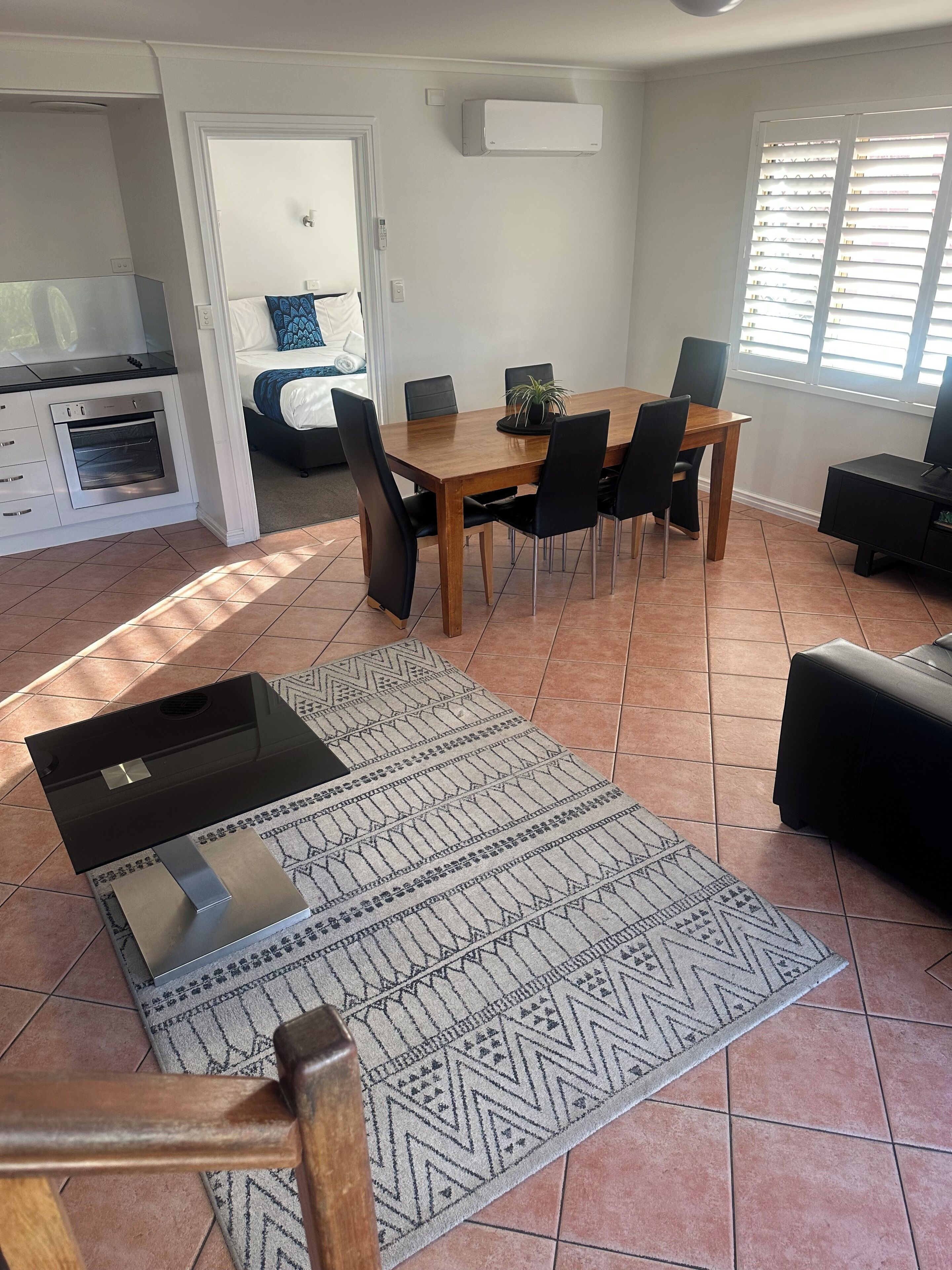 Een moderne woonkamer met een eethoek, een keuken met oven, en een televisie.