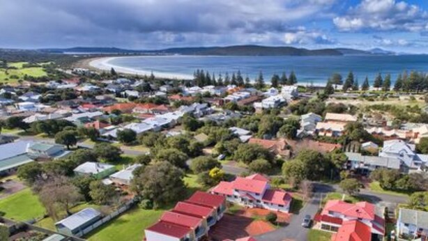 An aerial view of a coastal residential area with houses, roads, and a beach.