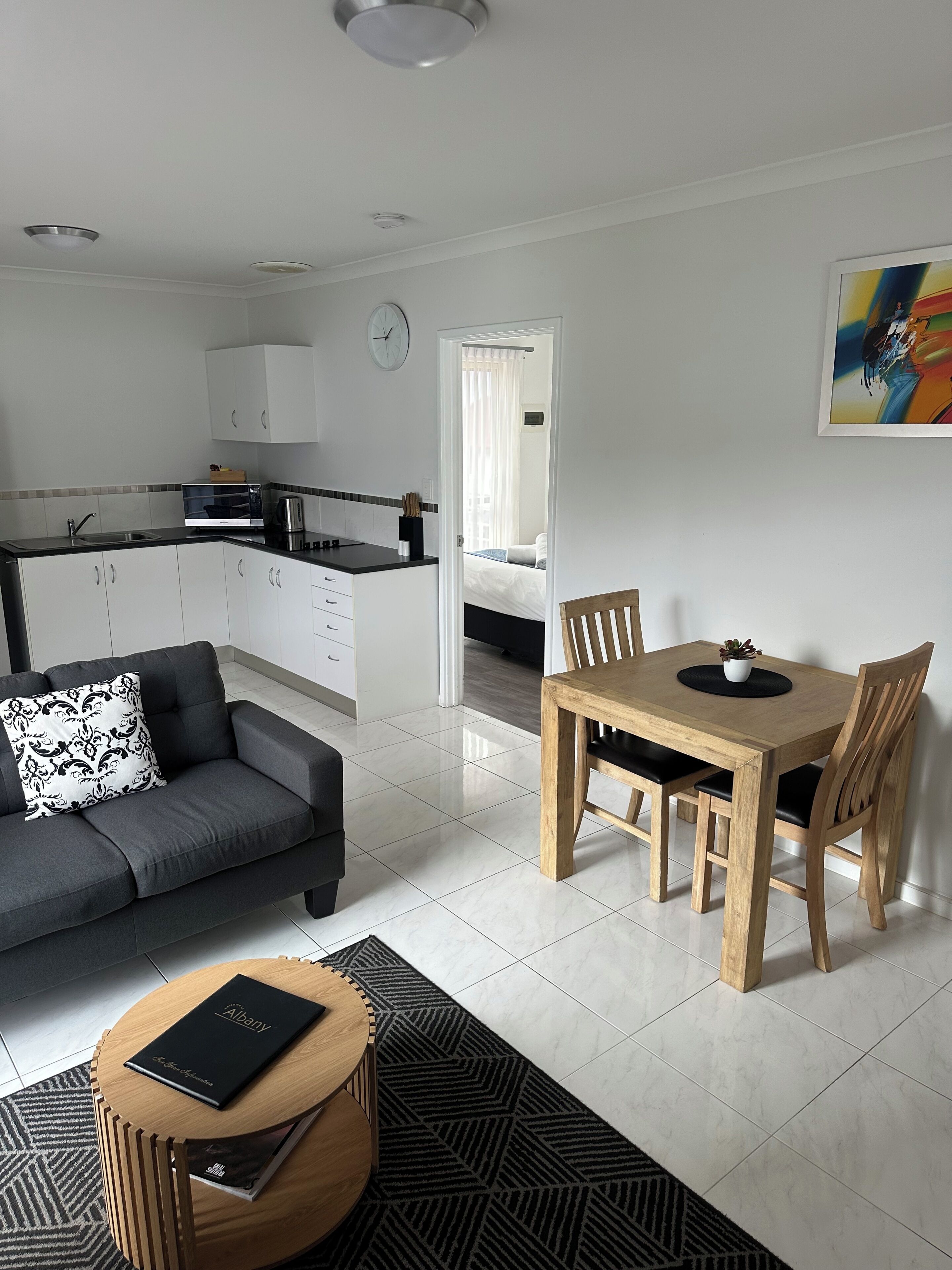 A modern living space with a sofa, dining table, and kitchen area.