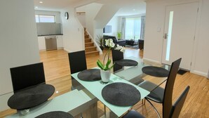 A modern dining area with a glass table, black chairs, and a potted plant.