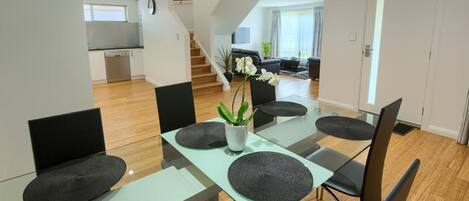 Een moderne eetruimte met een glazen tafel, zwarte stoelen en een potplant.