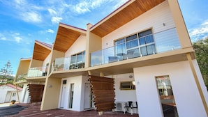 A modern multi-story building with balconies, large windows, and a clear sky.