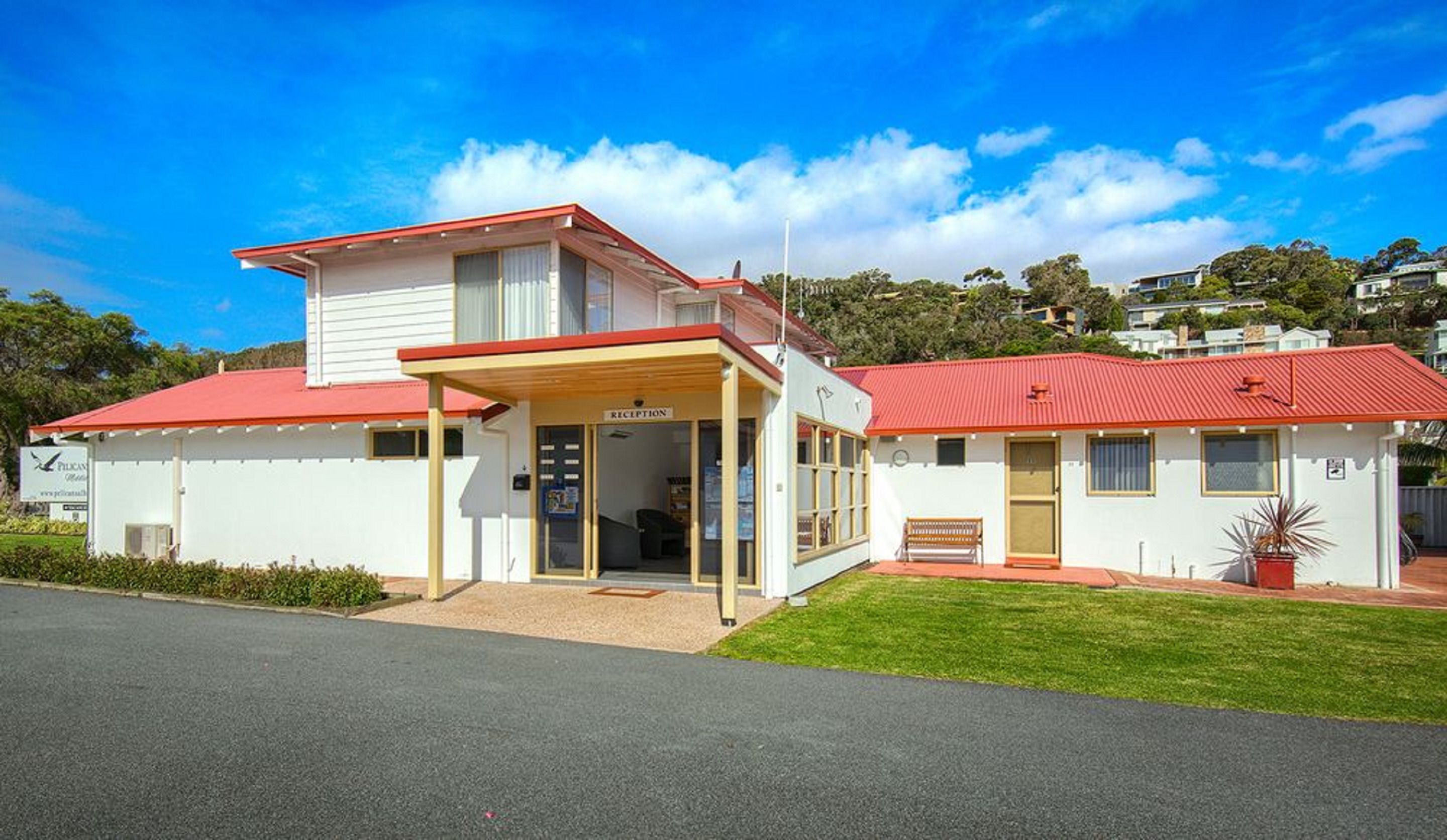 A two-story building with a reception area, a bench outside, and a red roof.