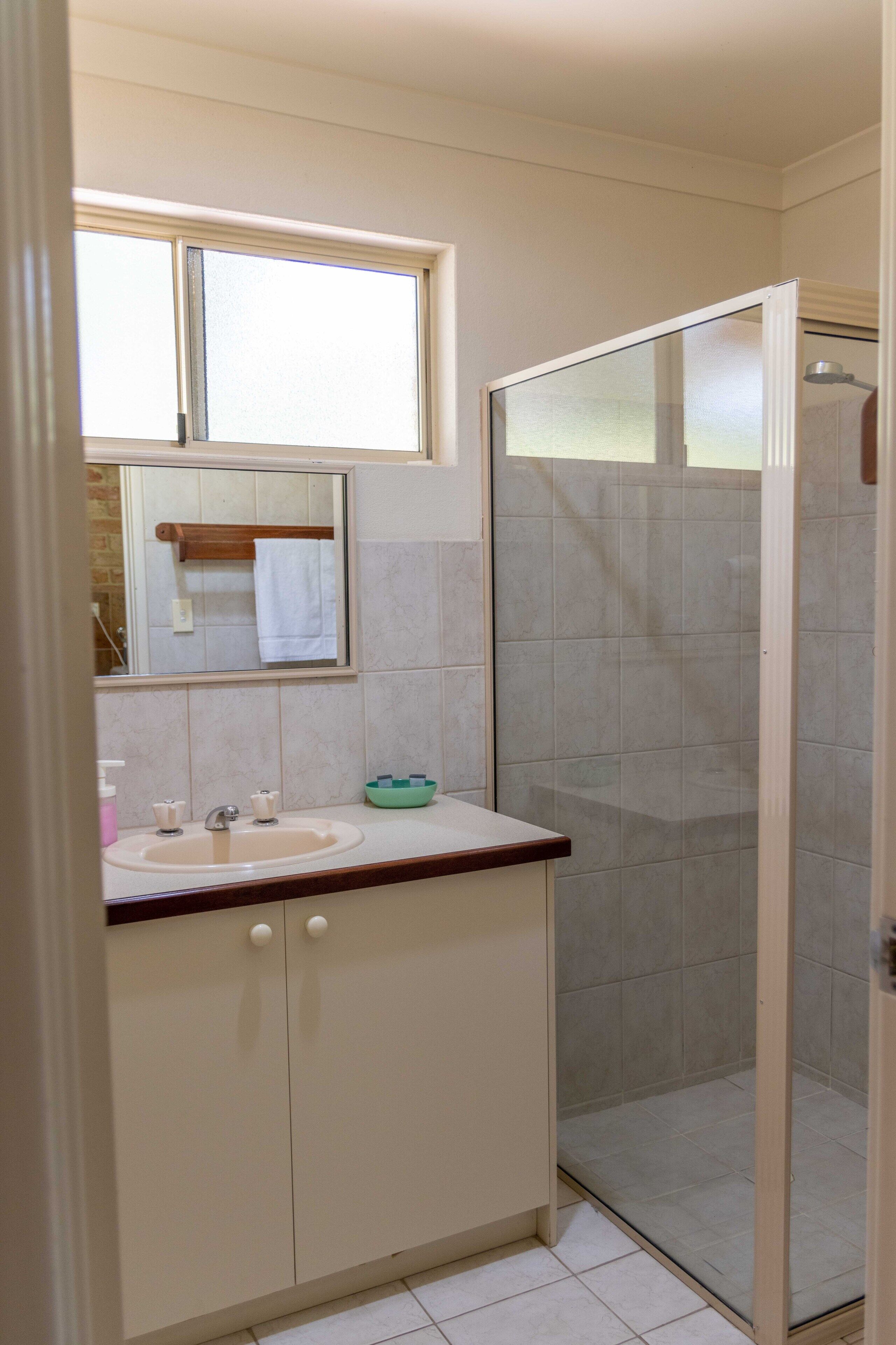 A bathroom with a sink, mirror, and shower.