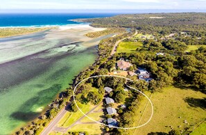 An aerial view of a coastal property with a road, houses, and a beach.