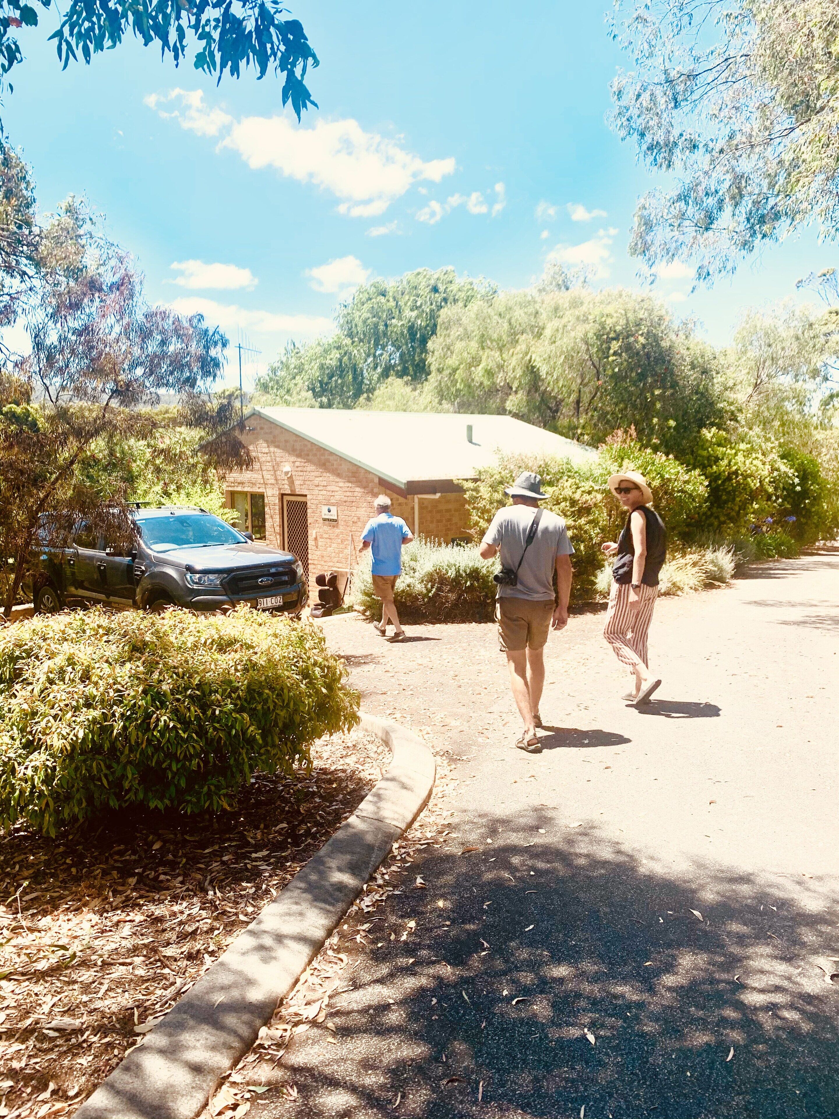 A residential street with houses, a parked car, and people walking.