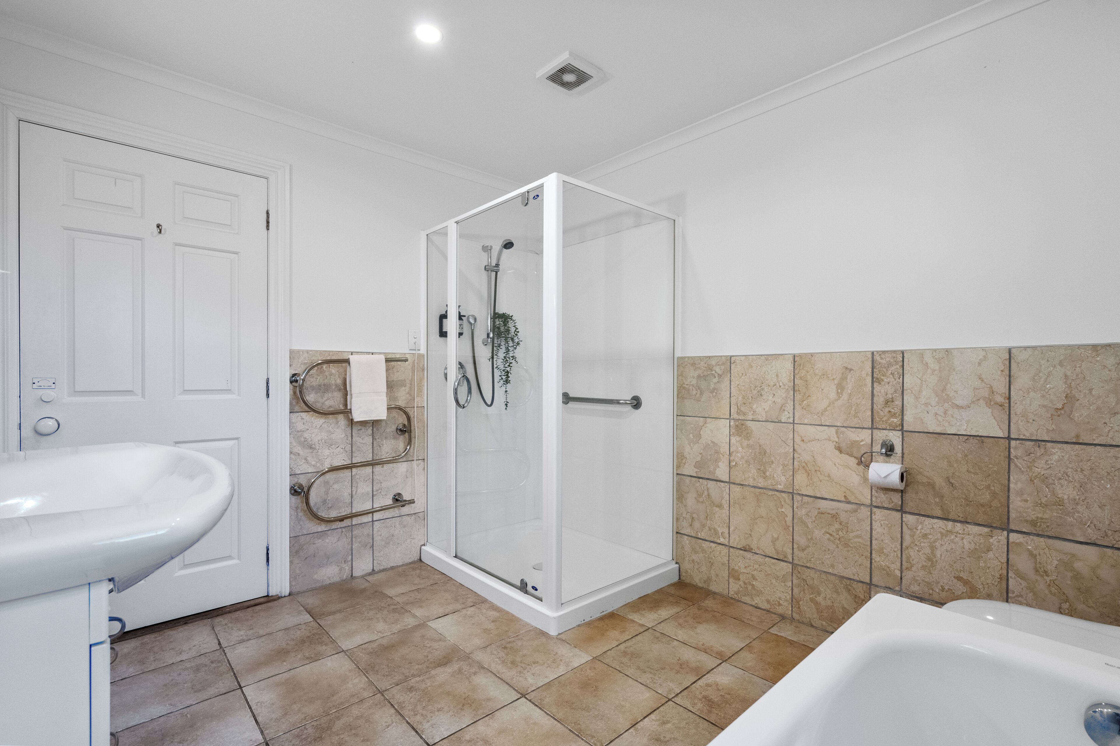 A bathroom with a glass-enclosed shower, a sink, and a bathtub.