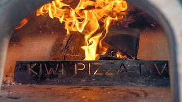 A wood-fired oven with the text "KIWI PIZZA OV" visible on the front.