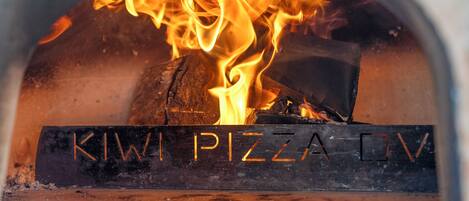 A wood-fired oven with the text "KIWI PIZZA OV" visible on the front.