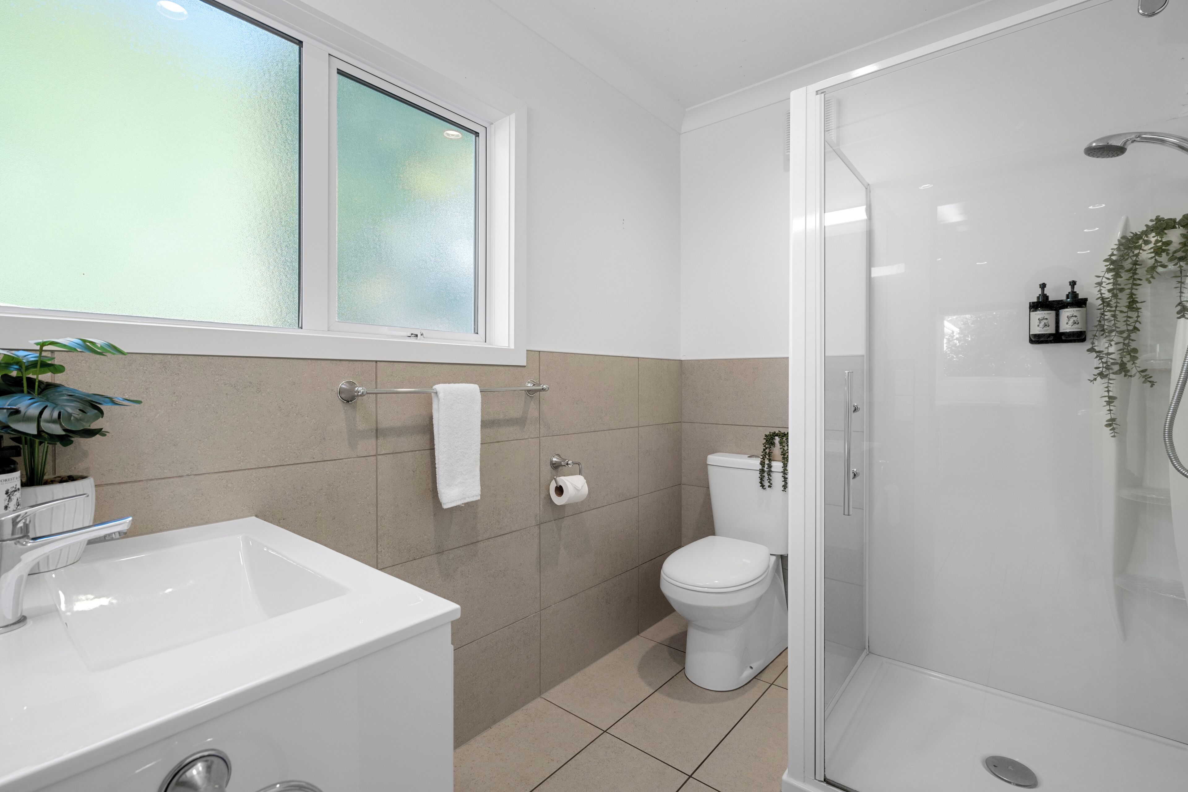 Un bagno moderno con doccia vetro, lavabo bianco e water.